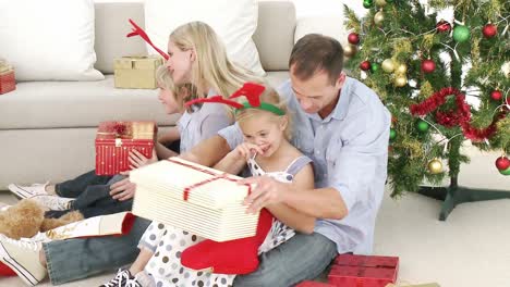 family opening christmas gifts in livingroom