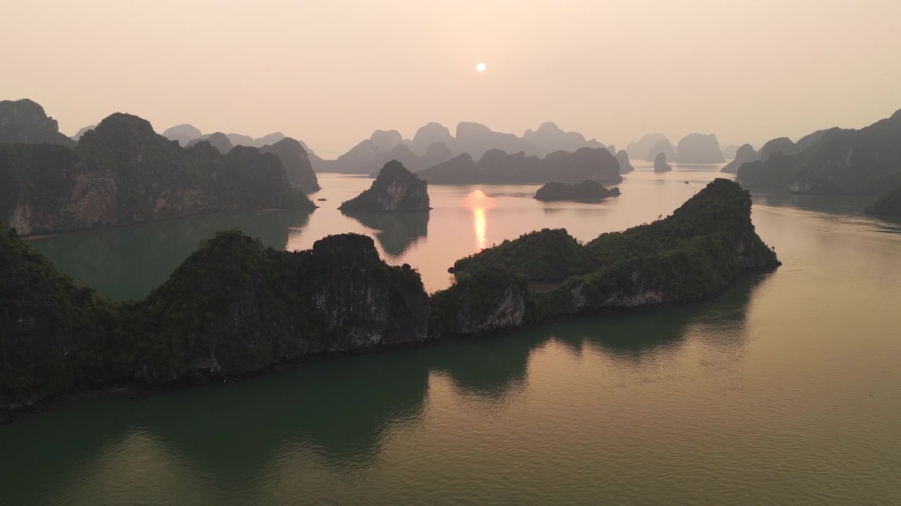 Cảnh quay trên không tiết lộ hoàng hôn Vịnh Hạ Long với những hòn đảo đá gồ ghề và cảnh biển vàng óng Việt Nam