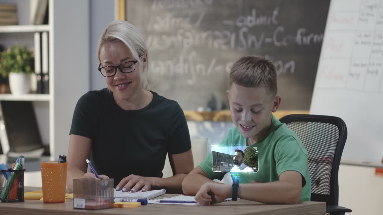 Student Using a Smartwatch for a Video Call. Medium shot of a male student using a smartwatch for a video call with his father while having a tutoring course