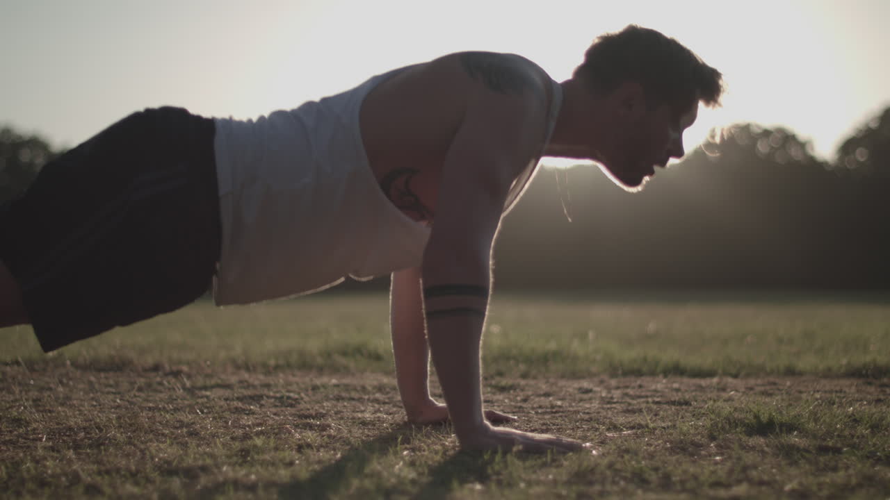 저녁 햇살에 공원에서 프레스 업을 하는 남자 - 등급 없음