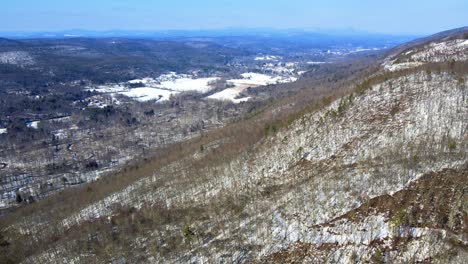 Imágenes-De-Video-De-Drones-Aéreos-De-Un-Valle-De-Montaña-Cubierto-De-Nieve-A-Principios-De-La-Primavera-Con-Cielos-Azules-Soleados