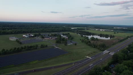 Imágenes-De-Drones-De-Los-Paneles-Solares-Instalados-Al-Costado-De-La-Carretera-Mientras-Pasan-Numerosos-Vehículos-Y-La-Carretera-Está-Rodeada-De-árboles-Y-Vegetación