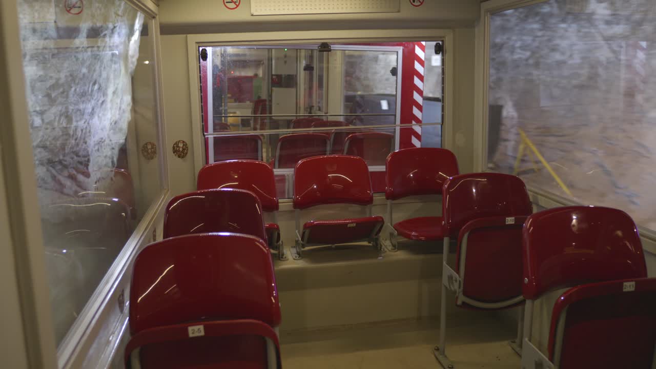 Discover the thrilling train ride through a historic underground mine, where visitors enjoy comfortable red seating huge windows, and stunning views of the mining operation.