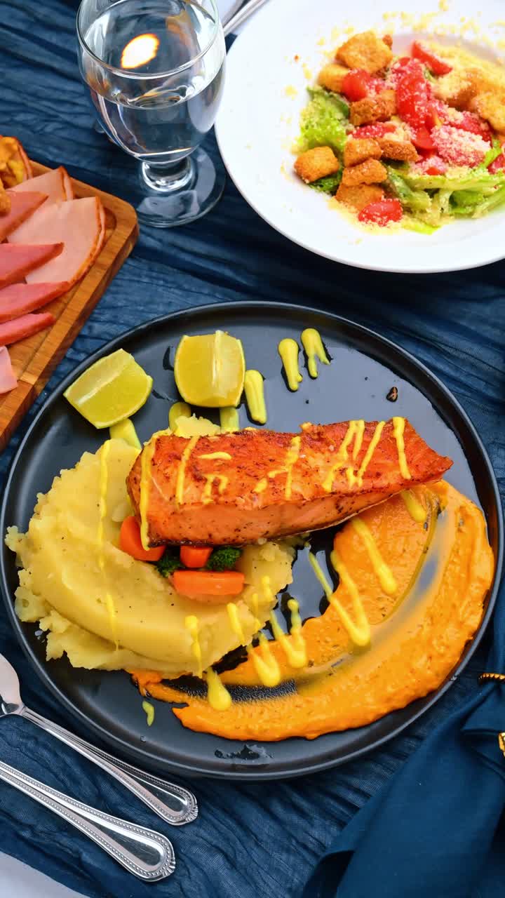 Filetto di salmone alla griglia con purè di patate e purea di verdure all'arancia. Trancio di salmone arrosto servito con purè e salsa su un piatto di ceramica nero.