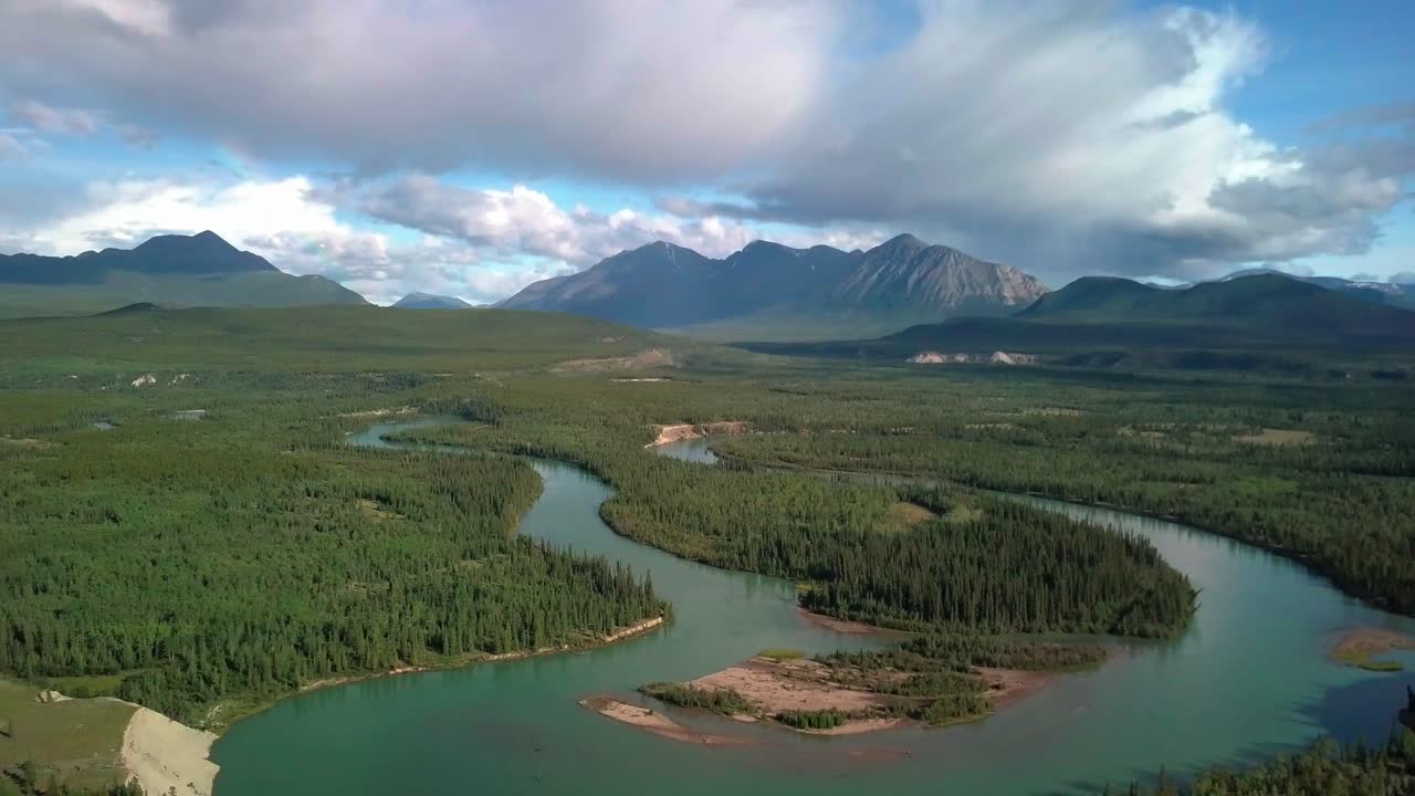 Breathtaking summer Yukon scenic backward flight above Takhini curvy river by evergreen tree forest in Ibex valley with epic view of majestic Mount Ingram, Canada, overhead aerial pull back