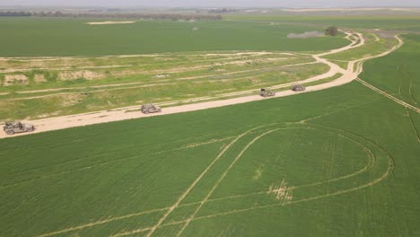 vista aérea de cuatro vehículos humvee blindados militares de la brigada de infantería golani israelí de las fdi conduciendo por un camino de tierra en un campo verde rural