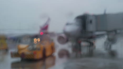 tractor de remolque y vista de la aeronave en un día lluvioso a través de la ventana de la terminal