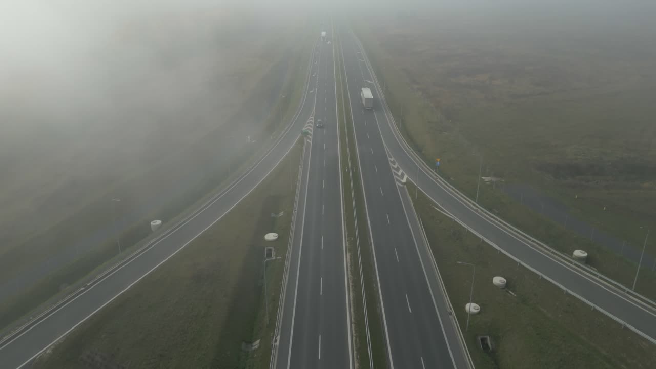 Vehicles driving on a foggy rural highway in early morning light, aerial view