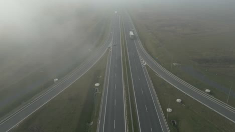 vehicles driving on a foggy rural highway in early morning light, aerial view
