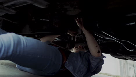 Woman-in-early-20s-checking-under-the-hood-of-a-truck-and-going-under-the-truck-to-find-and-fix-mechanical-problem