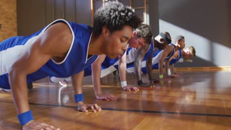 diverse male basketball team wearing blue sportswear and doing push ups