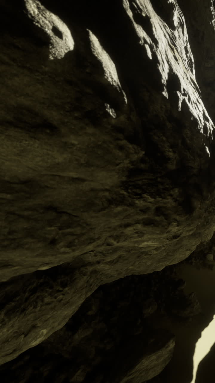 Parete rocciosa in una grotta con ombre e luce provenienti da un'apertura distante.