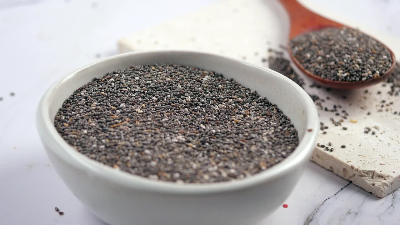 Semi di chia salutari in una ciotola e su un cucchiaio di legno