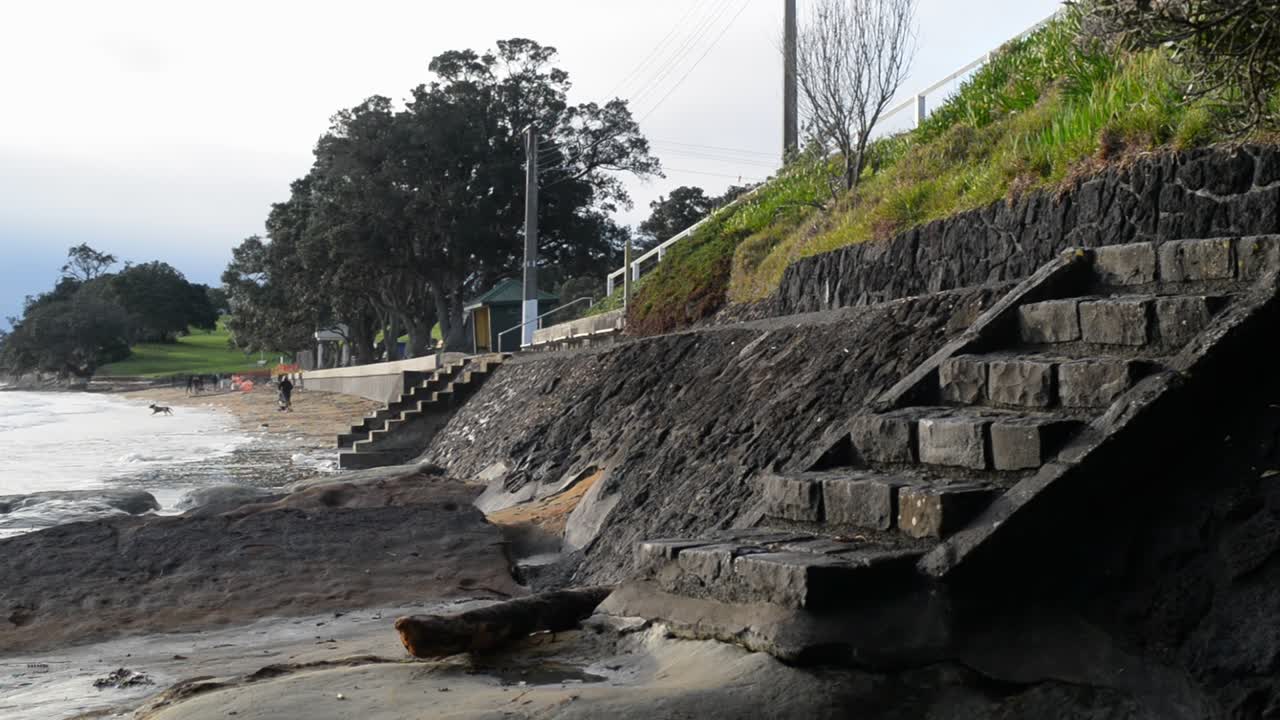 Concrete stairs that lead down to a rocky dog beach on a sunny morning