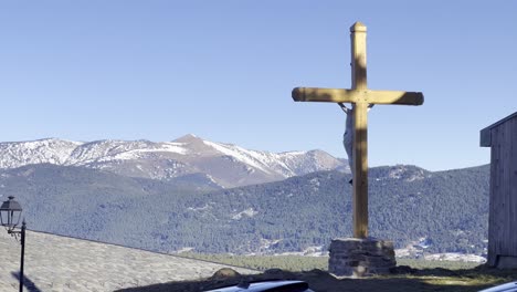 A static frame featuring a crucifix, with mountains in the background