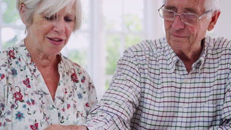 Senior-couple-doing-jigsaw-puzzle-at-home,-tiltshot