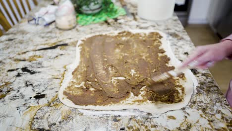 Spreading-the-cinnamon-and-brown-sugar-spices-on-dough-to-roll-into-cinnamon-buns