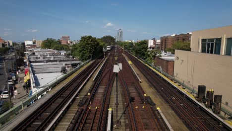 an aerial view of elevated train tracks with a train travelling towards the camera and another going in the opposite direction on a sunny day