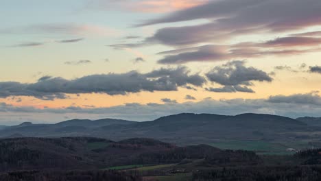 Lapso-De-Tiempo-Panorámico-De-Una-Formación-De-Nubes-Lenticulares,-Durante-La-Puesta-De-Sol,-Sobre-Un-Paisaje-Montañoso