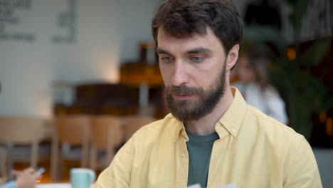 a male takes notes in his notebook in a coffee shop