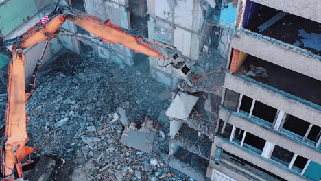 excavator crashing floors of an old building and dusty debris falling down. disassembling of collapsed structures. view from above.