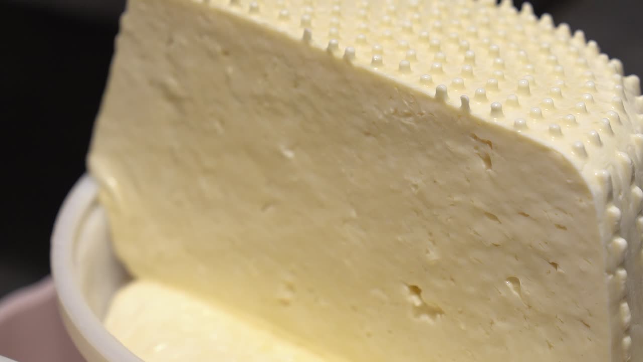 Freshly molded cheese block draining liquid from its bottom portion