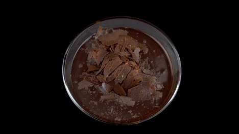 taza de pudín de chocolate girando en el fondo negro, video 4k