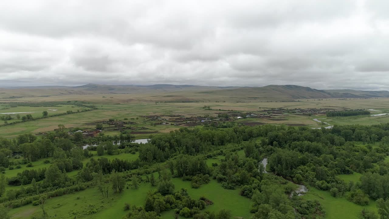 vista aérea de una aldea rural en un valle con un río y campos verdes