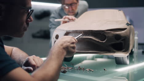 car design model being sculpted by two designers