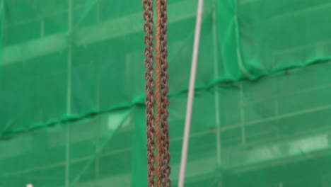 lifting chain and rope rising from the ground at construction site. tilt-up