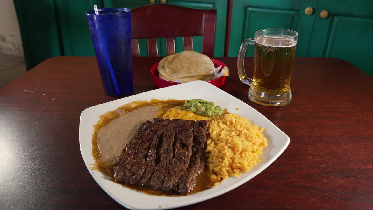 Tabletop dinner of cheese enchiladas tampiquenas plate with corn tortillas and beer, slider 4K