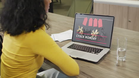 Biracial-woman-at-table-using-laptop,-online-shopping-on-cyber-monday,-slow-motion