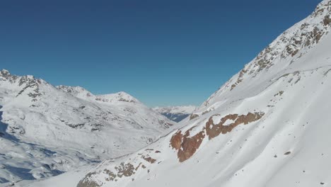 Aerial-view-around-snowy,-mountain-wall,-in-sunny,-Austria---circling,-drone-shot