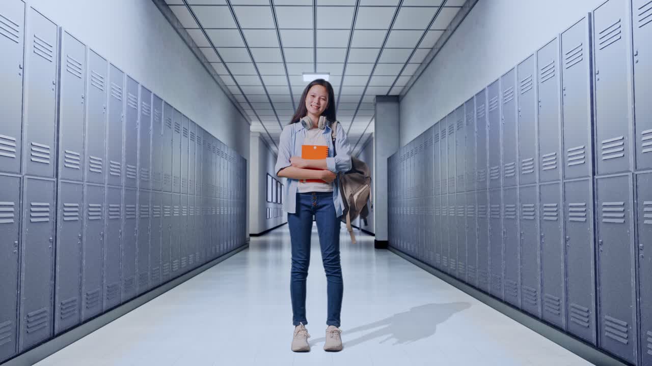 cuerpo lleno de estudiante adolescente asiática con una mochila sosteniendo algunos libros y sonriendo a la cámara mientras estaba de pie en el pasillo