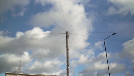 electric and telephone wires on the lamppost with clouds in the sky on the background