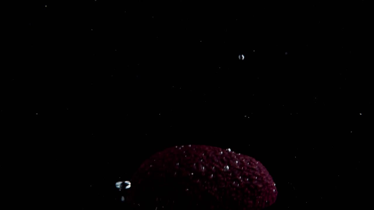 aguacate cayendo al agua en cámara superlenta, fondo negro, muchas burbujas de aire, 4k240fps