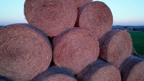 the hay bales, stacked in a pyramid, dry in the field at sunset.