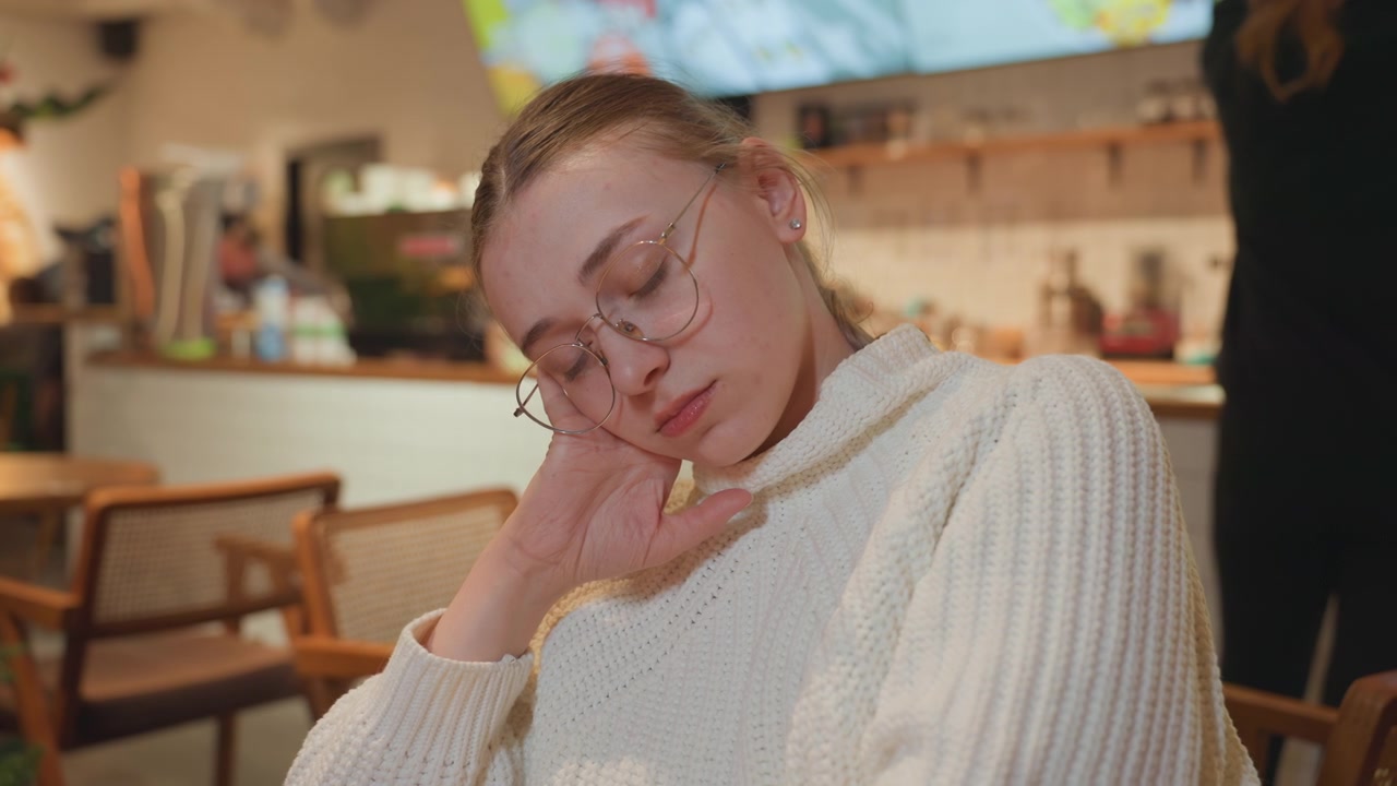 Giovane donna stanca che fa un pisolino in un accogliente caffè