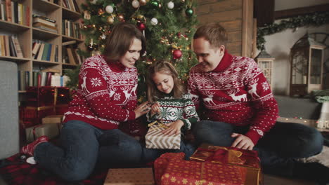 Glückliches-Kleines-Mädchen,-Das-Geschenk-Auspackt,-Während-Es-Mit-Seiner-Mutter-Und-Seinem-Vater-Zu-Hause-Vor-Dem-Weihnachtsbaum-Sitzt-2