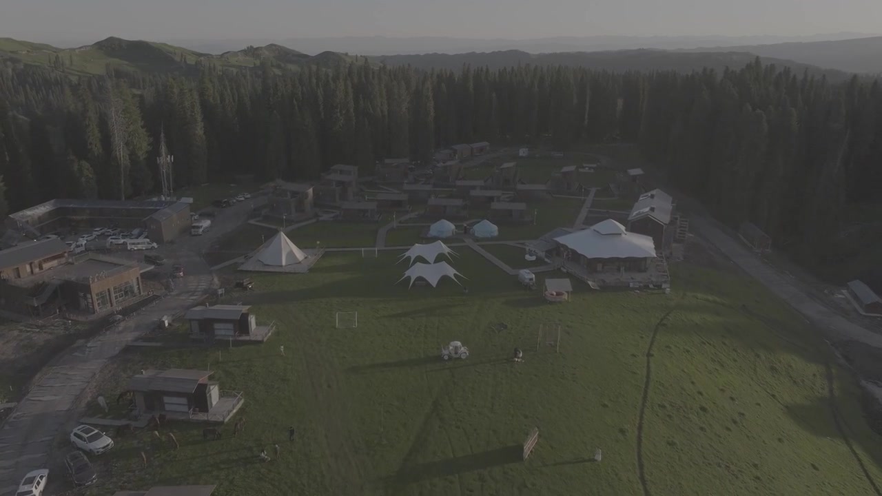 Ripresa aerea con drone che mostra lussuose cabine glamping circondate da una campagna ondulata e strade tortuose. Tranquillo rifugio rurale immerso tra campi verdi e foreste in Scozia alla luce della sera.