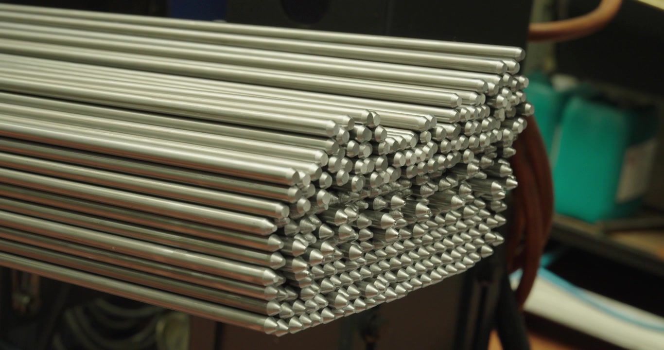 Close-up de barras de metal empilhadas em um armazém industrial, mostrando matérias-primas para fabricação, engenharia e metalurgia.