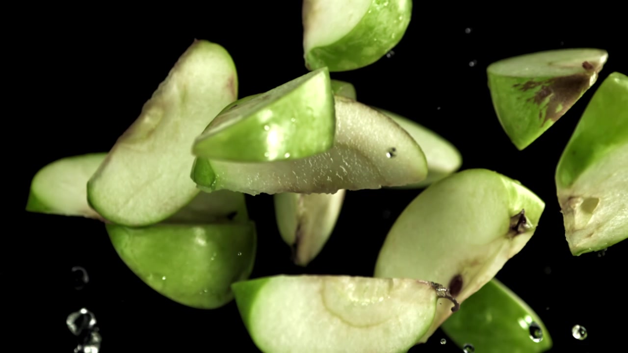 Super Slow Motion di fette di mela verde fresca in caduta con gocce d'acqua