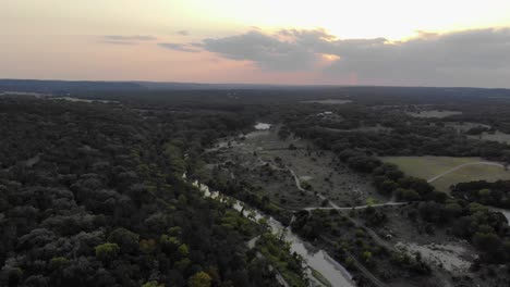 vuelo aéreo justo sobre campos, árboles, - río al atardecer