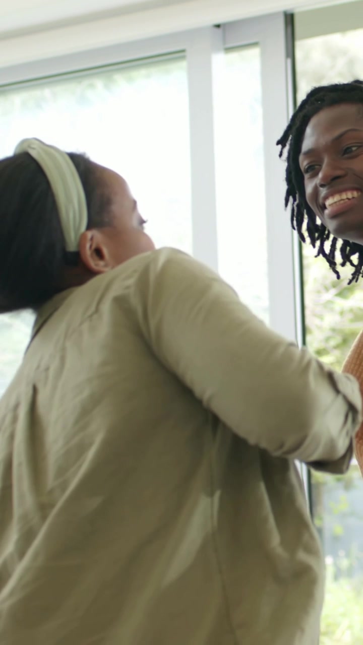 Vertical video: Greeting man arriving, woman in olive shirt headband reaching at sliding door