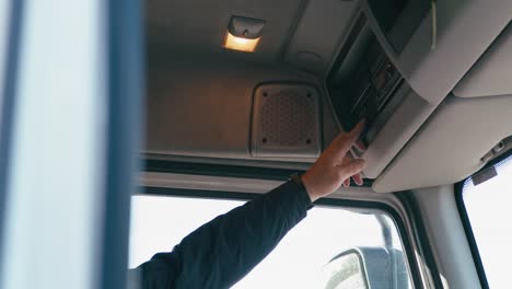 a hand of a man pushing various buttons in a truck