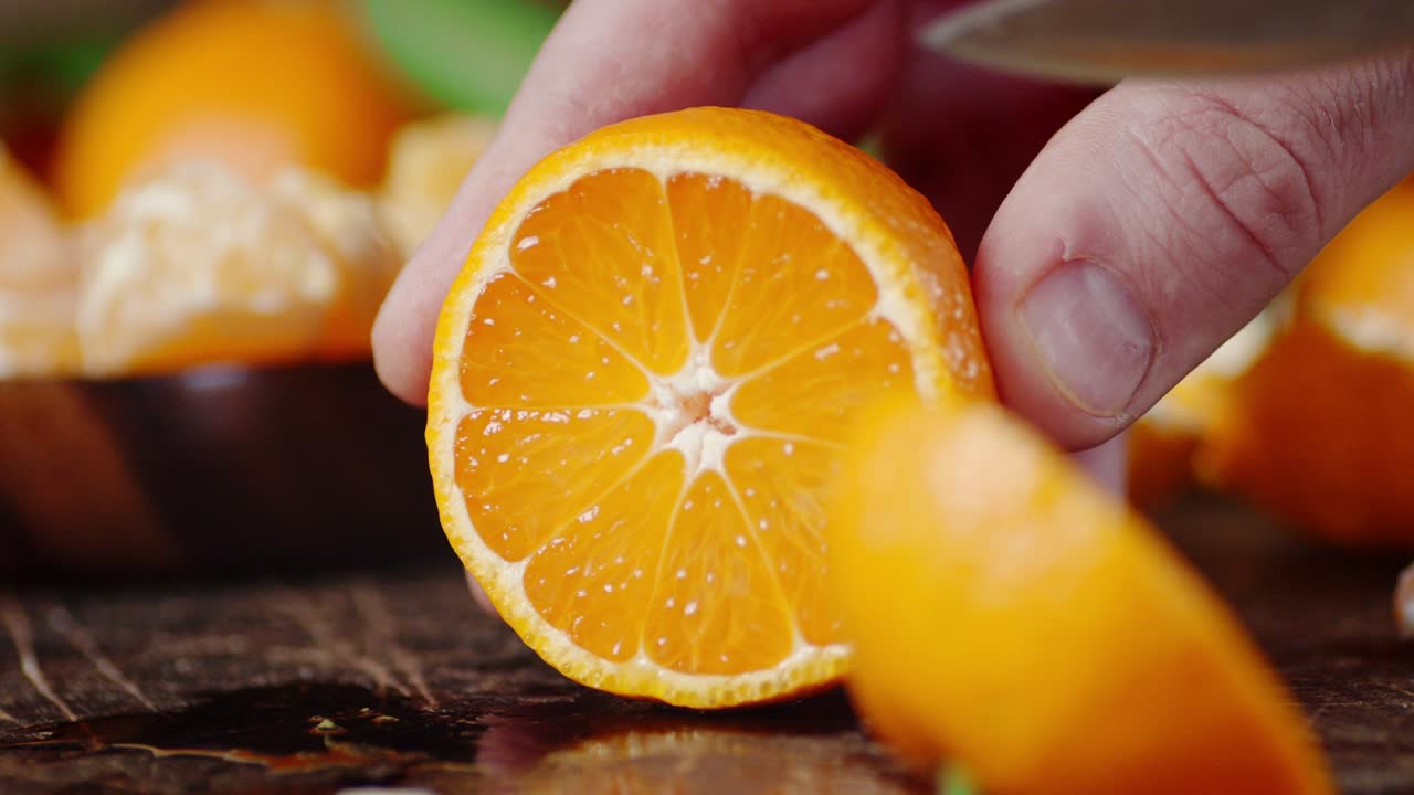 칼을 들고 있는 한 남자의 손이 만다린 한 조각을 잘라냈습니다.