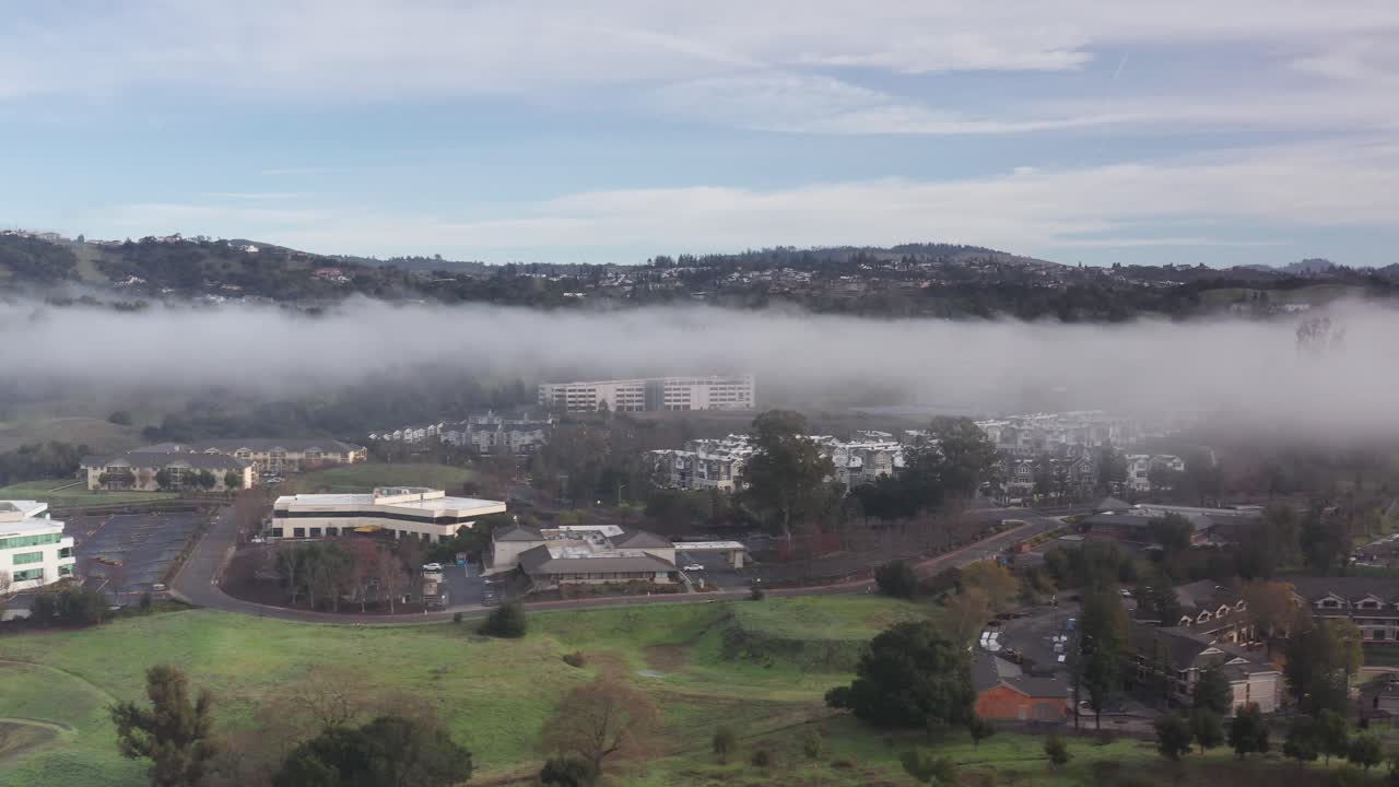 Aerial rising dolly shot of a fog-covered landscape with peeking hills in Santa Rosa, California. 4K