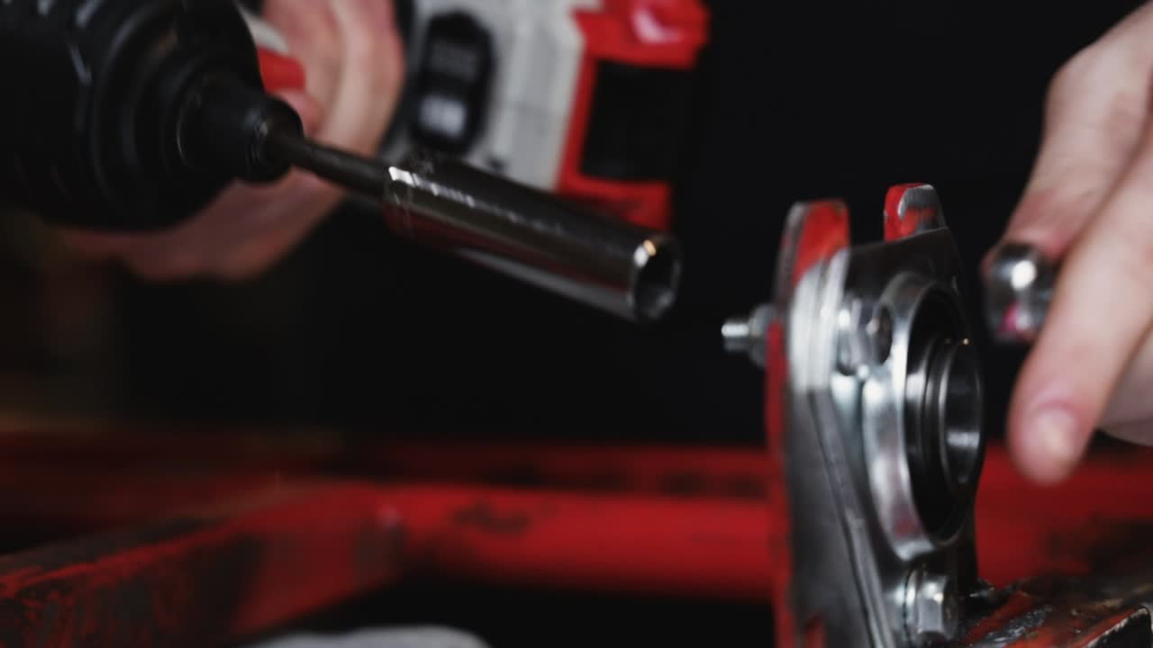 1인치 강철 튜브로 만든 금속 고카트 자동차 프레임을 분해하는 동안 일부 볼트를 풀고 있는 임팩트 드릴의 기계공 제작 작업장에서 클로즈업 샷