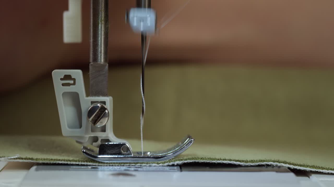 Close-up of Sewing Machine Needle Stitching Green Fabric