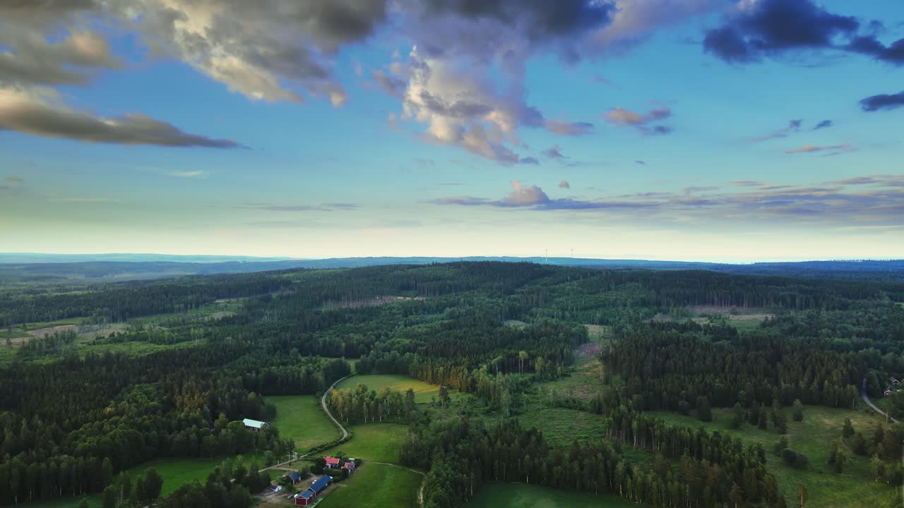vista panorámica del paisaje rural con bosques de coníferas, campos verdes y cielo azul nublado cerca de hjo, suecia - toma aérea